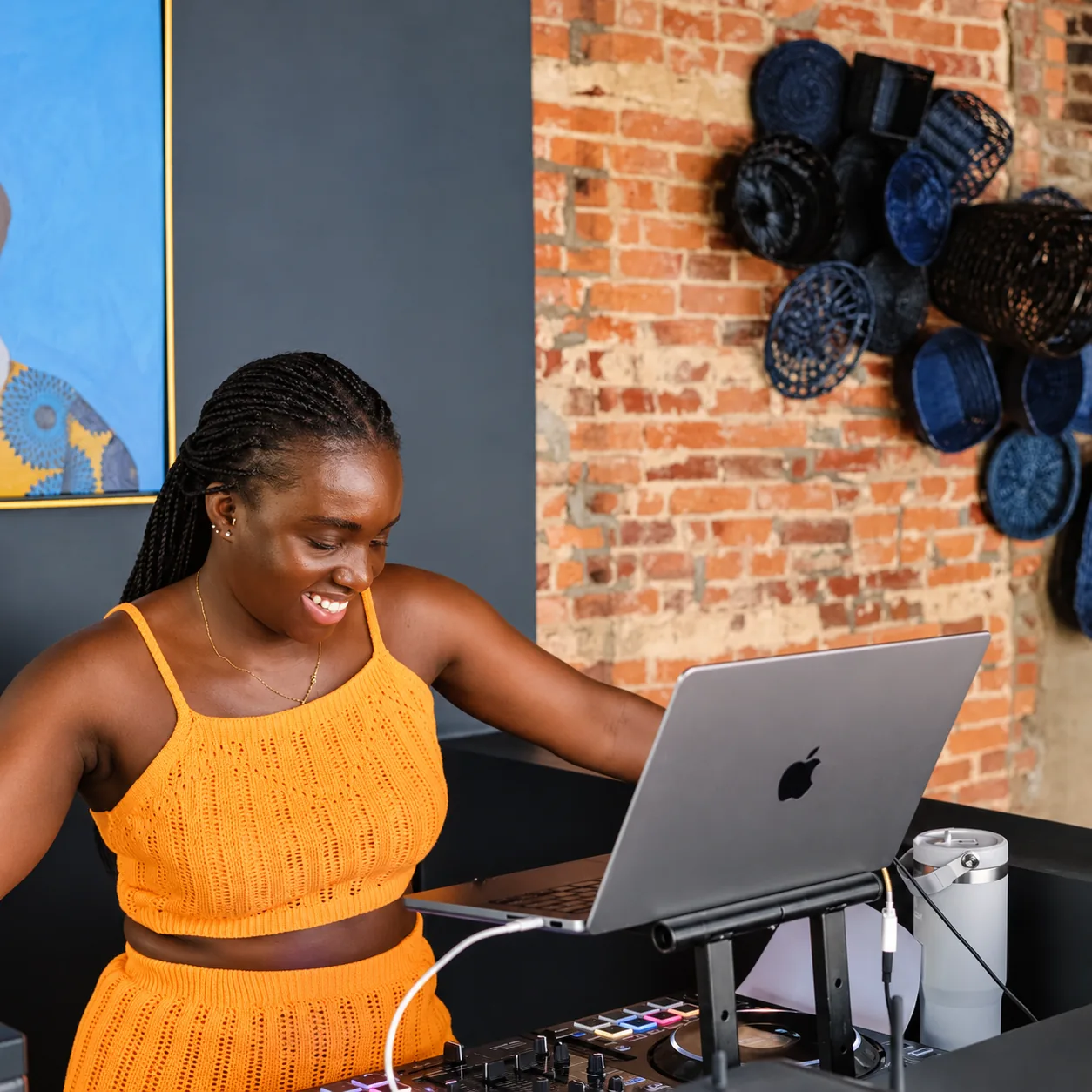 DJ Akuaa smiling at a DJ booth in a creative loft