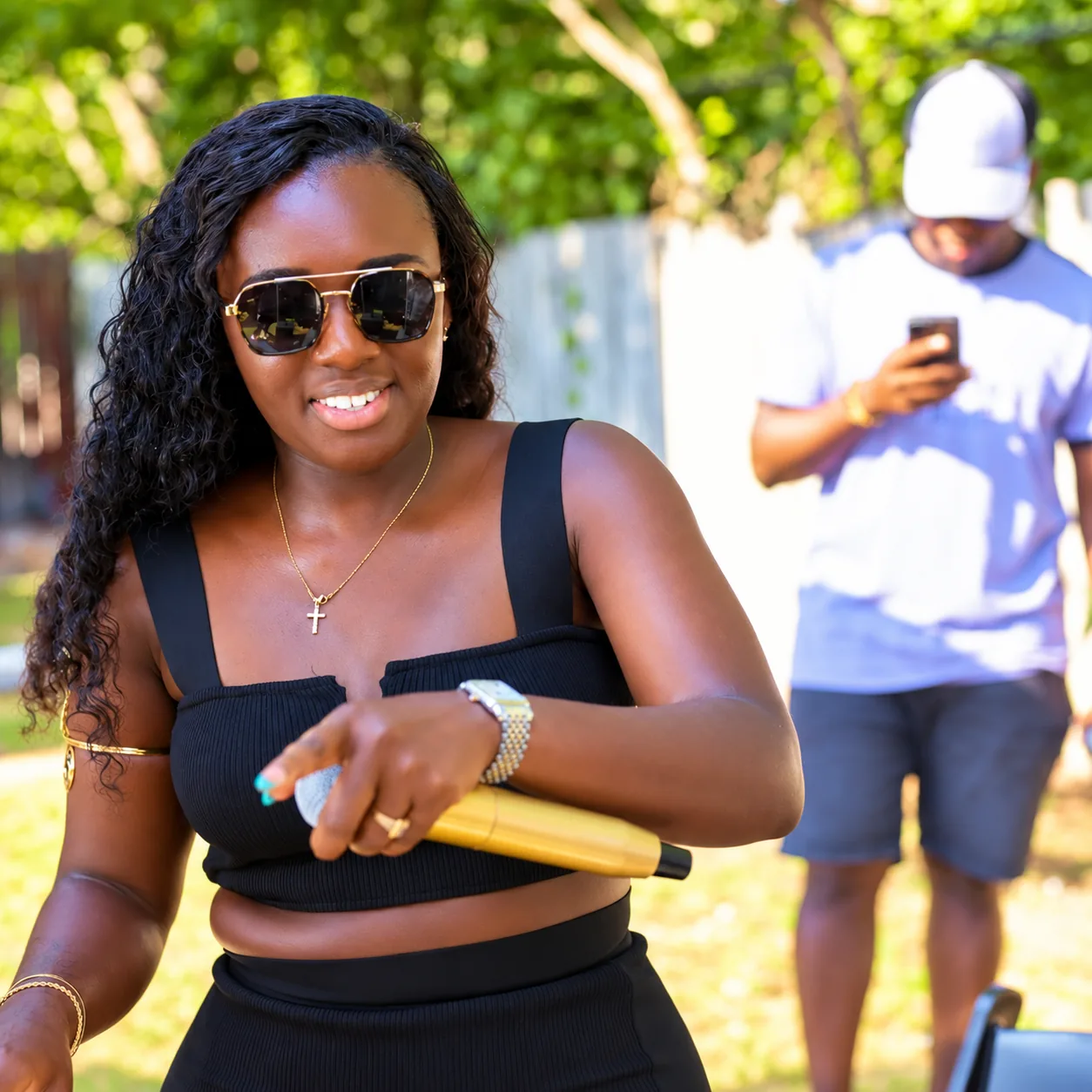 DJ Akuaa holding a gold microphone at an outdoor garden event
